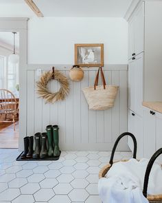 a white tiled floor in a room with boots hanging on the wall and a basket