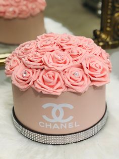 a chanel box with pink roses in it sitting on a white furnishing