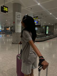 a woman is pulling her luggage through the airport with her hand on the handlebars