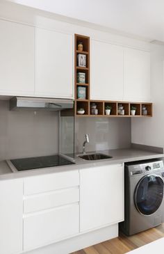 a washer and dryer in a small room with white cupboards on the wall