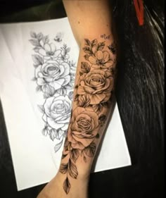 a woman's arm with flowers on it and an ink pen in the background