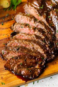 steak sliced up on a cutting board with garnish and seasoning next to it