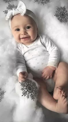 a baby laying on top of a white blanket with snowflakes around her feet