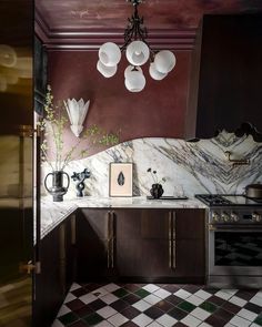 a kitchen with marble counter tops and dark wood cabinets, an ornate chandelier over the stove