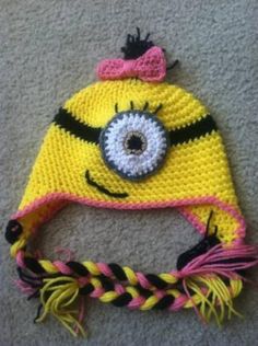 a crocheted hat with an eye and braids on the bottom, sitting on carpet