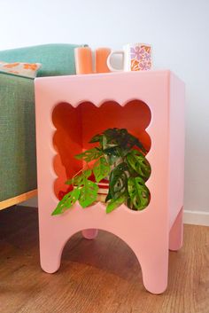 a pink plant stand with a potted plant in it