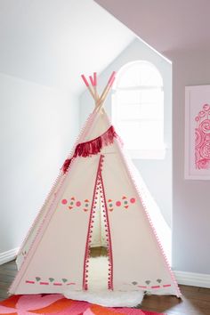 a teepee tent with pink trim and tassels