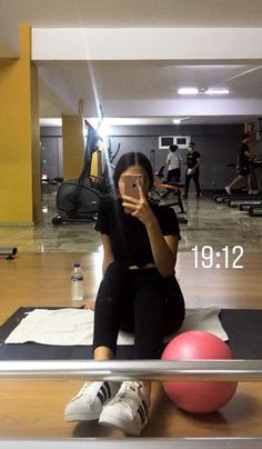 a woman taking a selfie while sitting on a gym ball with her cell phone