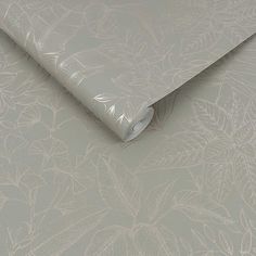 a roll of white paper on top of a wallpaper covered in leafy designs