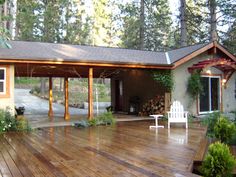 a wooden deck in front of a house with a white lawn chair on top of it