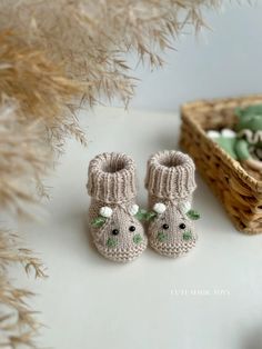 a pair of knitted baby shoes sitting next to a basket filled with green and white items