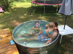 two children in a large metal tub with their faces painted to look like they are swimming