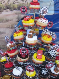 cupcakes are arranged in the shape of cars and trucks on a cake stand