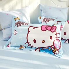 two hello kitty pillow cases on top of a bed with white sheets and blue pillows