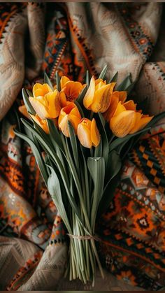 a bouquet of yellow tulips sitting on top of a blanket