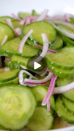 a white bowl filled with sliced cucumbers and red onions on top of it