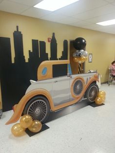 an old fashioned car with balloons in the shape of city skylines on display at a children's birthday party