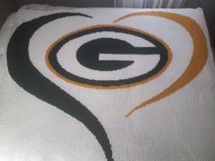 the green bay packers logo is on top of a white bed sheet with black and orange swirls