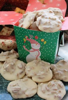 some cookies are in a green box on a blue and pink tablecloth with snowmen