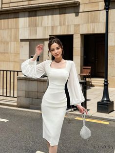 a woman is walking down the street wearing a white dress with bell sleeves and heels