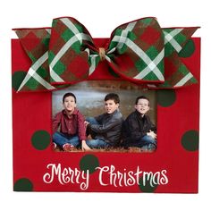 a red frame with green and white polka dots on it that says merry christmas in front of two boys