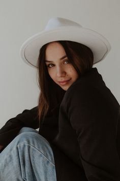 a woman wearing a white cowboy hat sitting on the floor