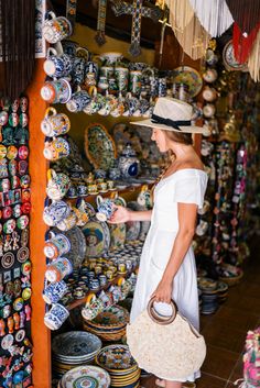 a woman standing in front of a store filled with lots of plates and bowls on display