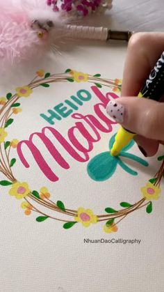 someone is drawing the word hello mama on a canvas with marker pens and some pink flowers