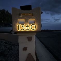 a mailbox with the number 1380 lit up at night in front of a car