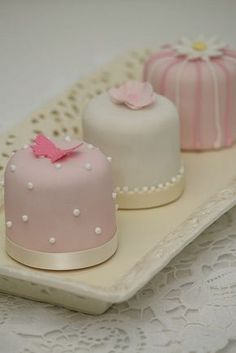 three small cakes sitting on top of a white plate with lace doily around them