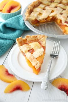 a slice of peach pie on a white plate with a fork next to the pie