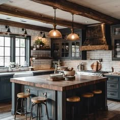 a kitchen with blue cabinets and wooden counter tops, two stools in front of the island