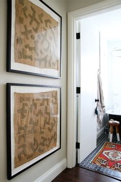 two framed art pieces hang on the wall above a door in an entryway area