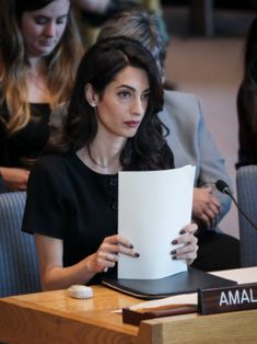 a woman sitting at a table holding up a piece of paper