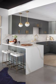 a modern kitchen with marble counter tops and stainless steel appliances, along with bar stools