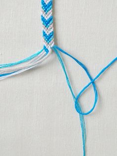 the instructions for how to make a bracelet with blue and white thread, including an arrow