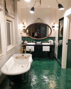 a bath room with a tub a sink and mirrors