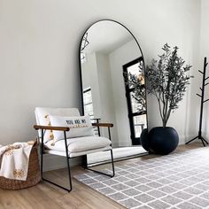 a white chair sitting in front of a mirror on top of a wooden floor next to a plant