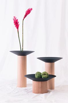 two wooden vases with flowers in them sitting on a white surface next to each other