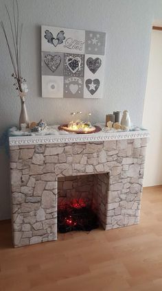 a stone fireplace with candles on it and some pictures above the fire in the wall