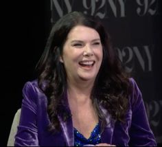 a smiling woman sitting in front of a black background