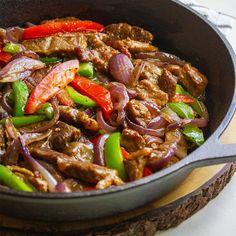 a skillet filled with meat, peppers and onions