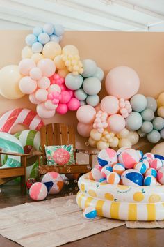 an assortment of balloons and toys on the floor in front of a wall with a balloon arch