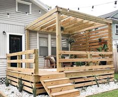 a wooden deck in front of a house with steps leading up to the back door