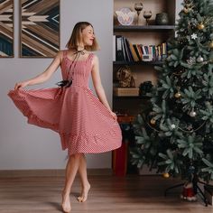 a woman standing in front of a christmas tree wearing a red and white striped dress