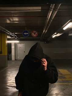 a person in a black hoodie is walking through a parking garage