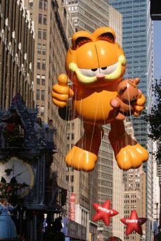 an inflatable cat balloon floats through the city