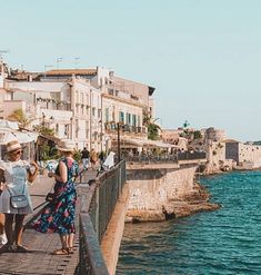 some people are standing on a pier by the water