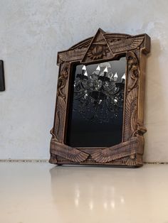 an ornate wooden frame with a chandelier hanging from it's side on a wall