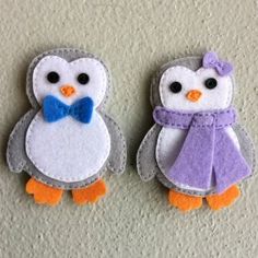 two small felt penguinies with bows on their heads, one wearing a purple scarf and the other in a blue bow tie